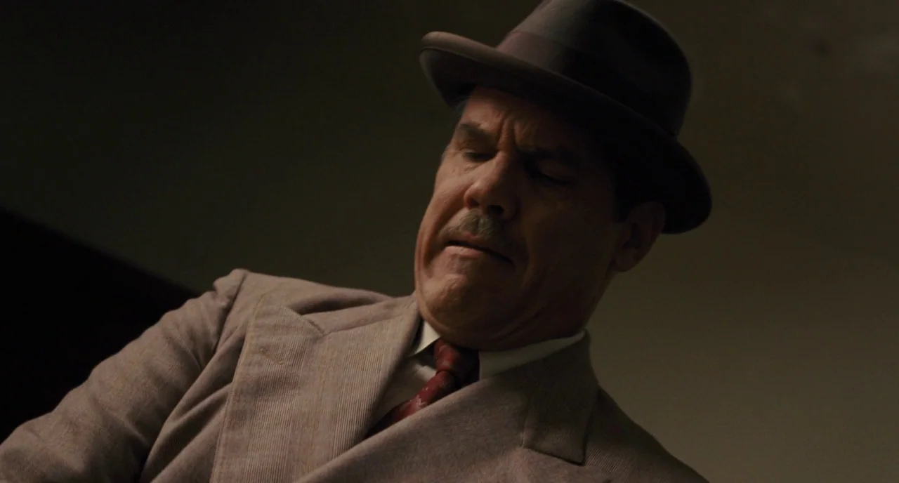 Hail, Caesar! (2016) movie still: medium — A man in a 1940s-style suit is seen in a dark interior space. He tilts his head downward with his eyes…