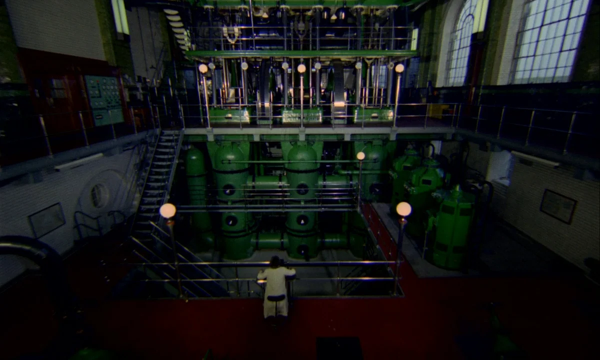 Wonderwall (1968) movie still: wide — A vast industrial engine room features towering green machines and high arched windows. A person in a light…