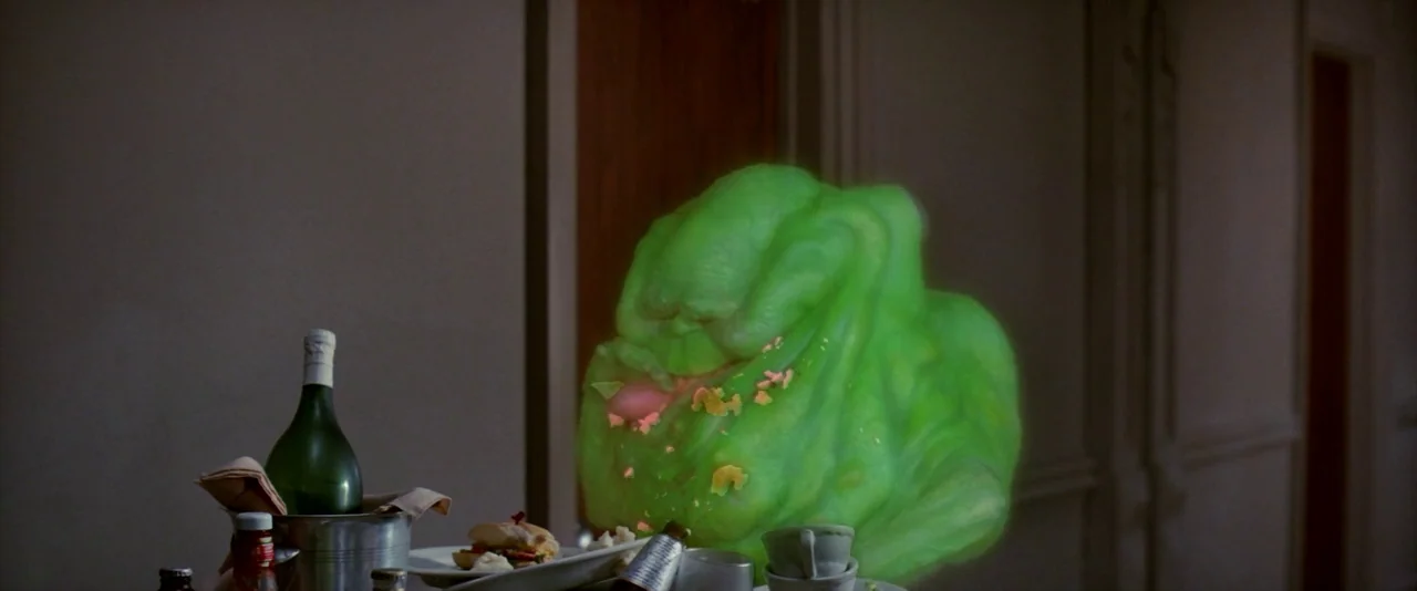 Ghostbusters (1984) movie still: medium — A dimly lit room features a silver food cart holding drinks and leftovers. A luminous, semi-transparent…