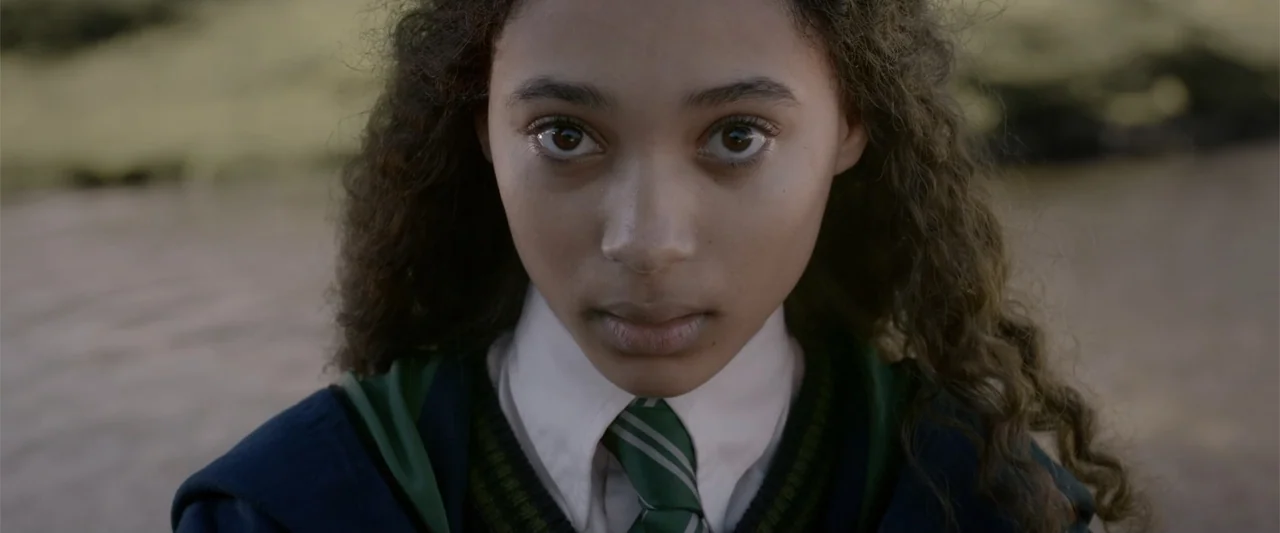Fantastic Beasts: The Crimes of Grindelwald (2018) movie still: closeup — A student stands outdoors in a school uniform against a blurred…