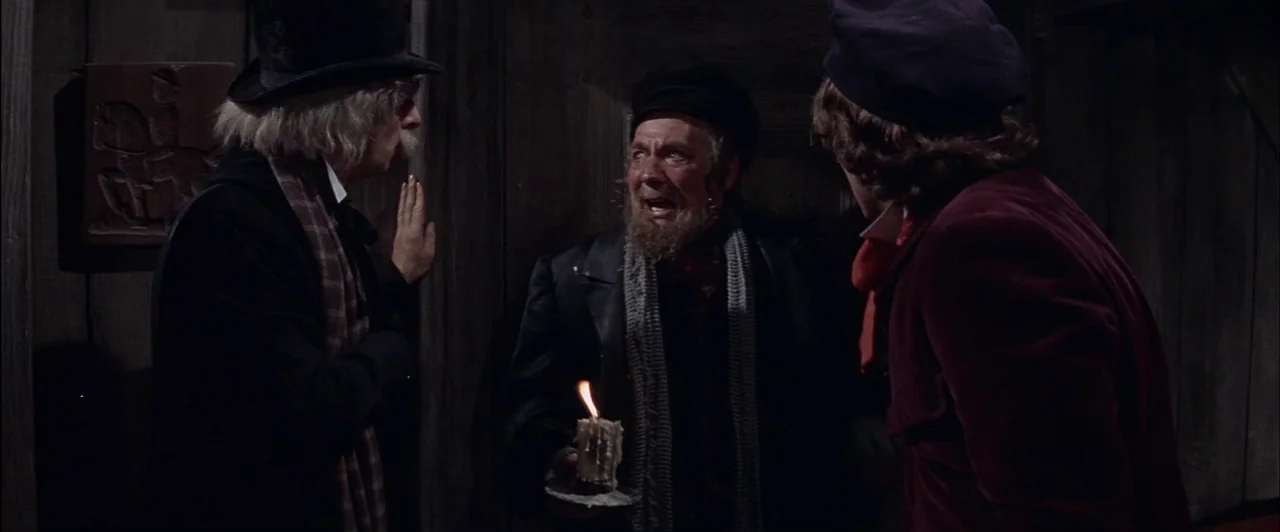 The Fearless Vampire Killers (1967) movie still: medium — A dark wooden hallway with vertical plank walls and a relief carving on the wall. Three…