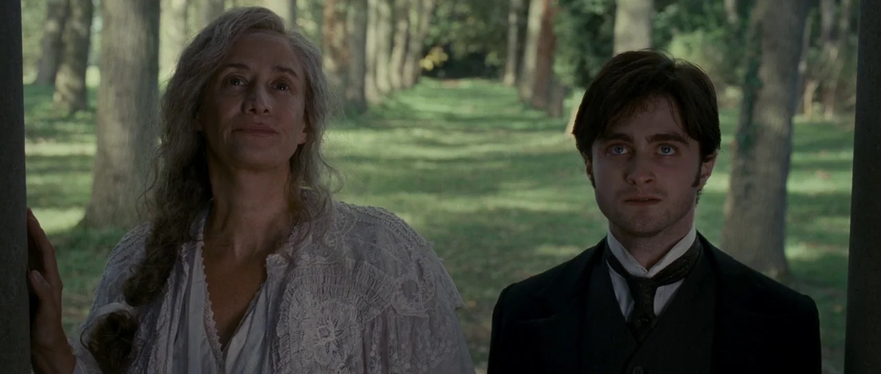 The Woman in Black (2012) movie still: medium — A tree-lined pathway with green foliage and tall trees extending into the distance. A middle-aged…