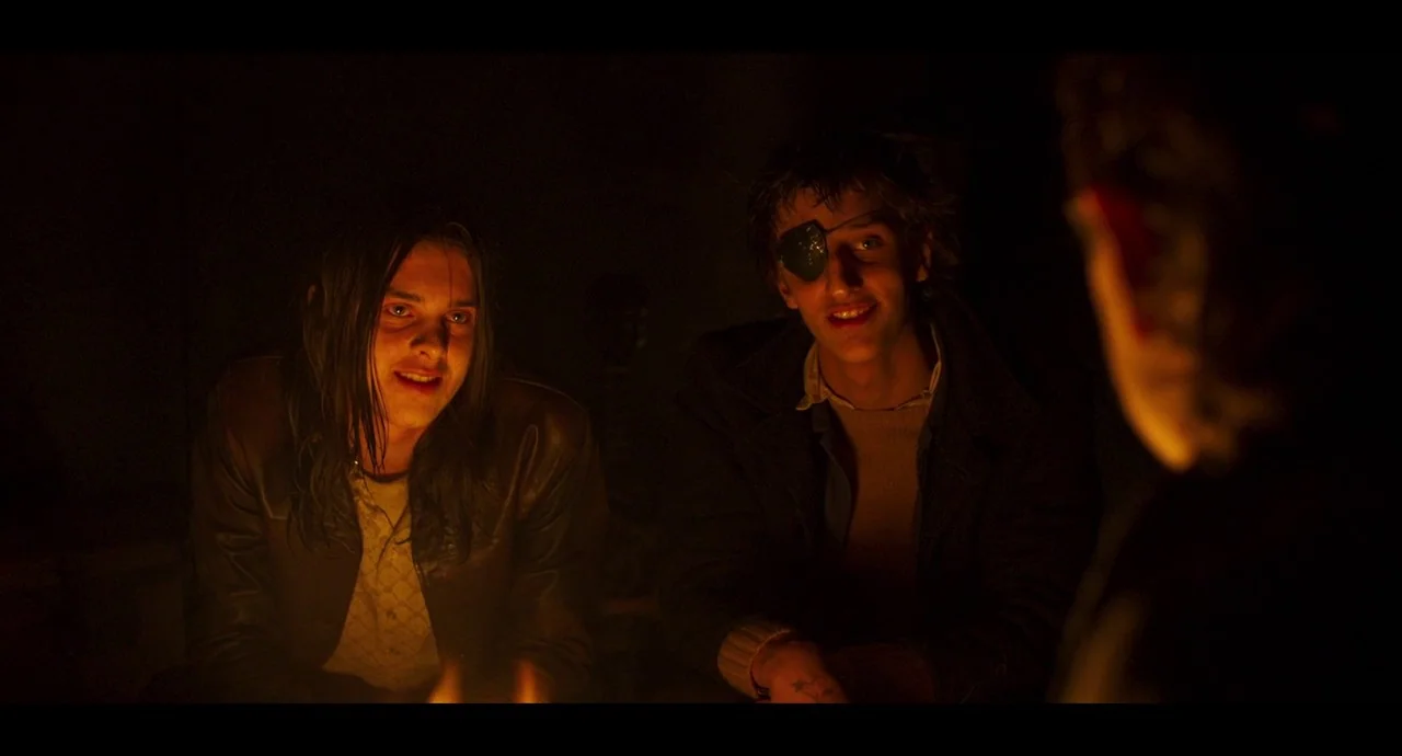 True History of the Kelly Gang (2019) movie still: medium — Two men sit together in darkness around the warmth of an unseen campfire. The flickering…