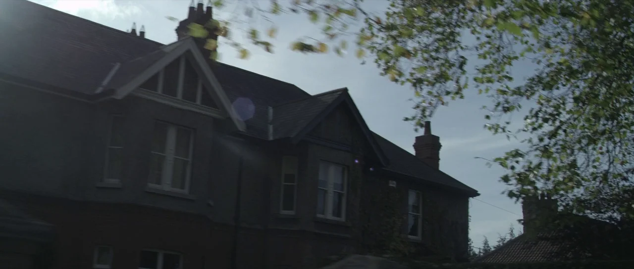 What Richard Did (2012) movie still: establishing — A two-story residential house with dark tile roofing and grey exterior walls stands outside.…