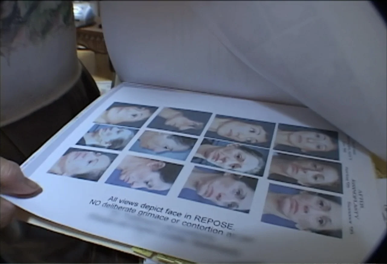 Plastic Disasters (2006) movie still: closeup — An interior space contains a document showing a grid of small medical photographs. A pair of hands…