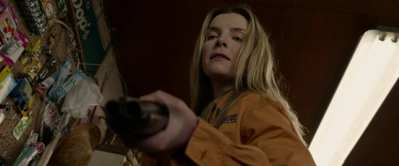 The Hunt (2020) movie still: medium — A dark retail space features a pegboard wall filled with various retail products. A woman in a tan work shirt…