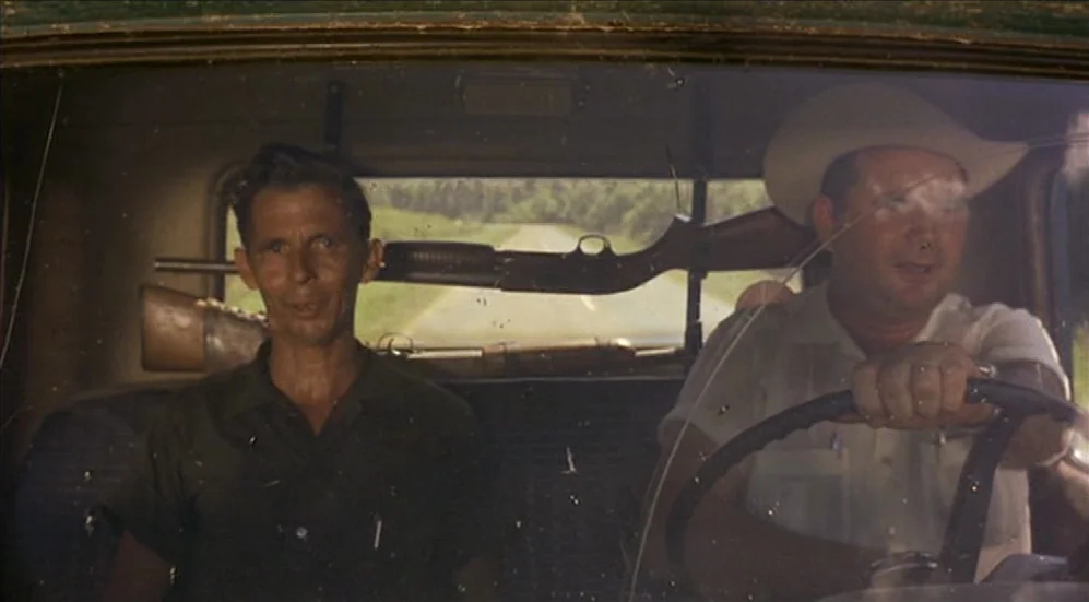 Easy Rider (1969) movie still: medium — A view from the windshield of a vintage truck moving along a rural road. Two men sit inside the cab with a…