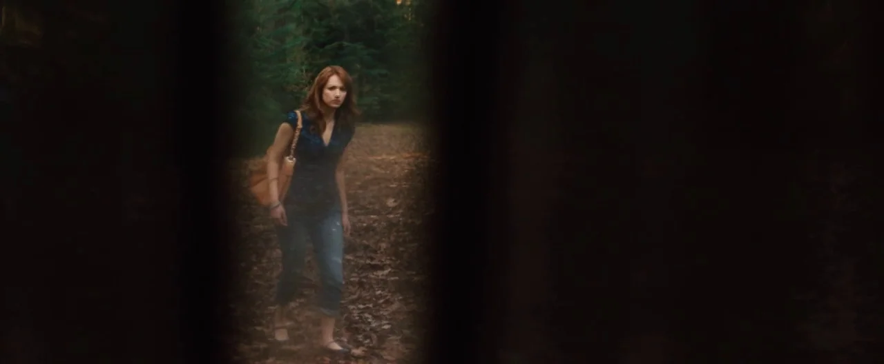 The Cabin In The Woods (2012) movie still: medium — A woman walks through a wooded area on a leaf-covered path. She moves forward while passing…