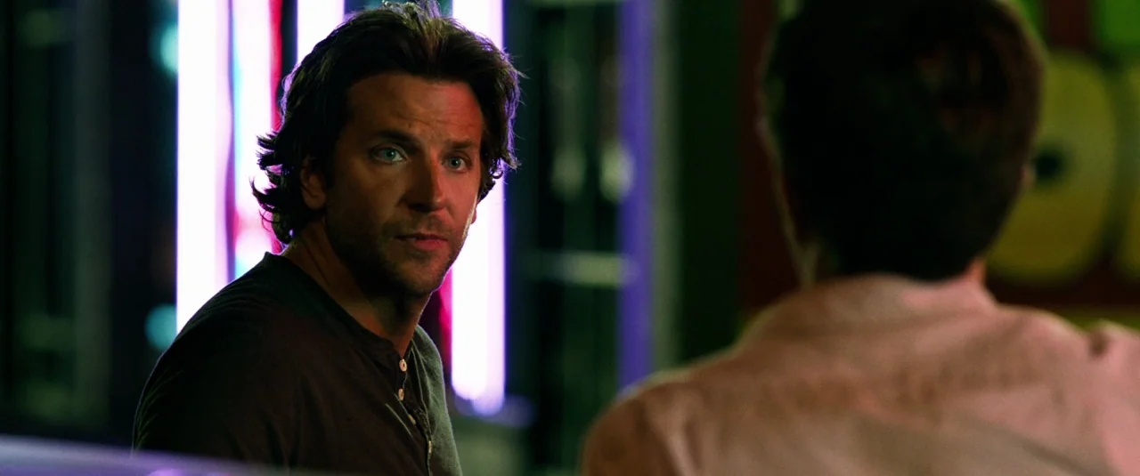 The Hangover Part III (2013) movie still: medium — A night scene outside with vivid purple neon lighting reflecting on a man's face. He looks toward…