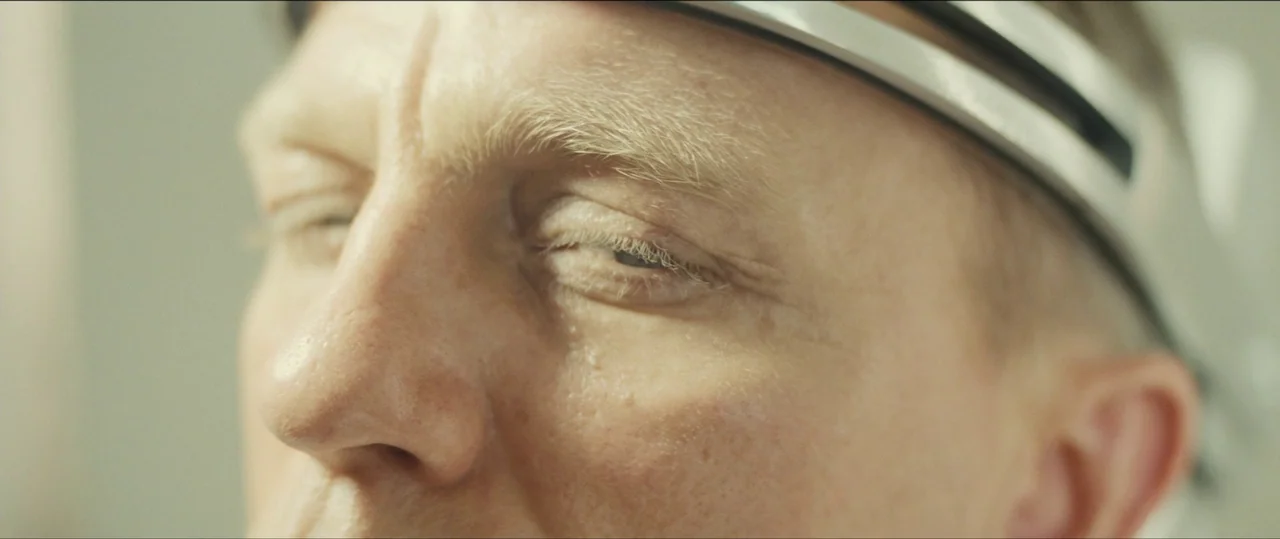 Spectre (2015) movie still: closeup — A close view of a person with blonde features in a brightly lit room. The individual is wearing a dark…