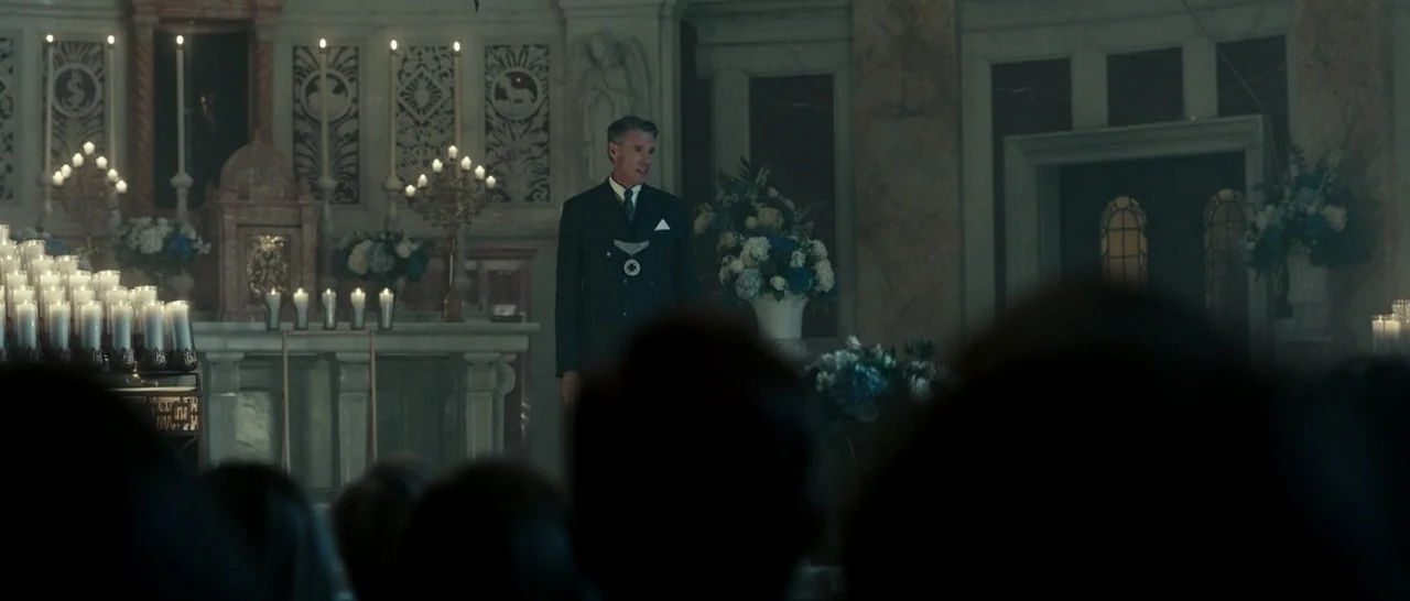 The Purge: Election Year (2016) movie still: medium — An ornate stone-pillared altar is decorated with numerous lit candles and blue floral…