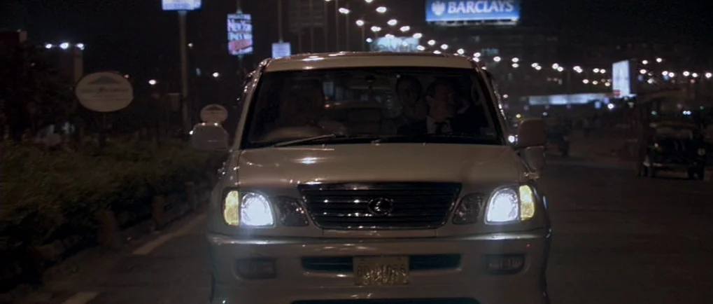 A Mighty Heart (2007) movie still: medium — A dark urban road at night features glowing street lamps and a Barclays advertisement sign. A white…