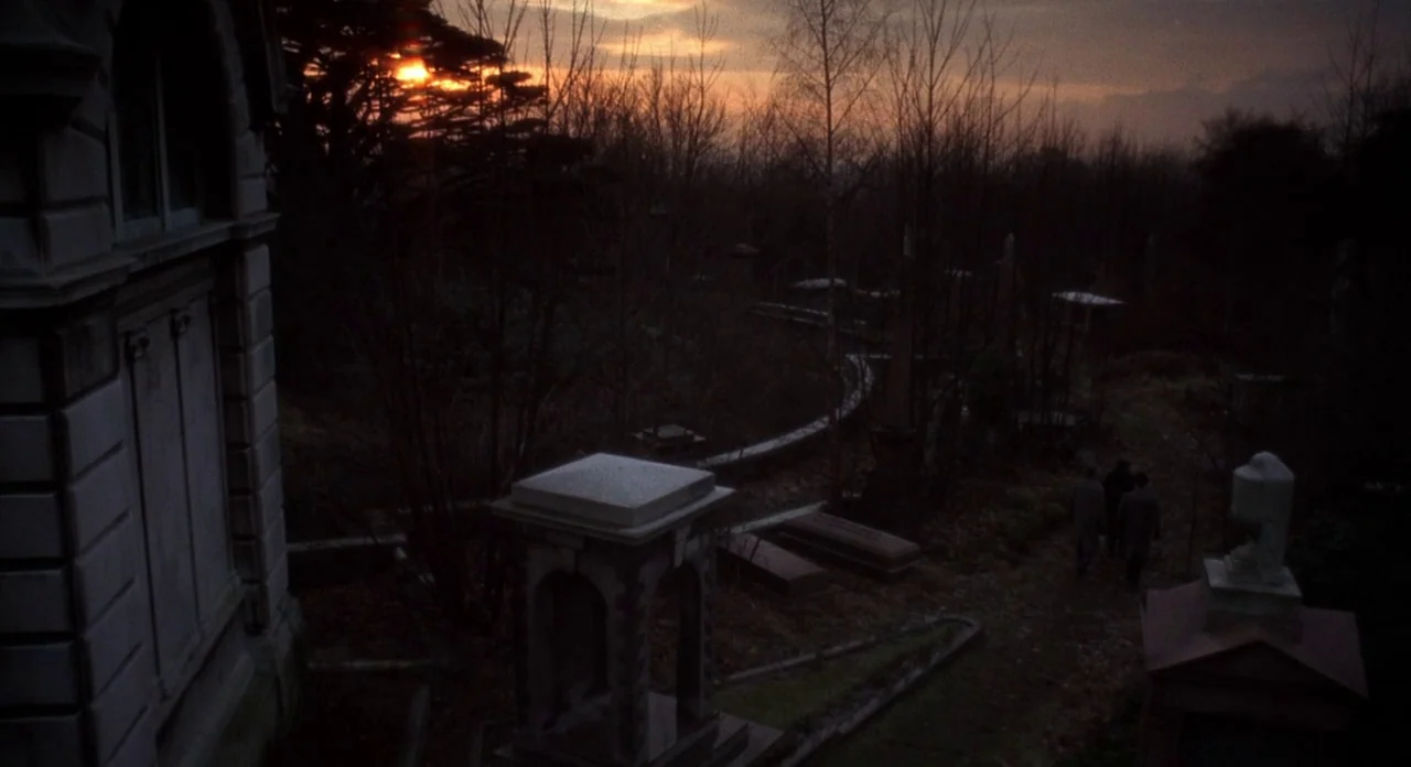 The Abominible Dr. Phibes (1972) movie still: establishing — An overgrown cemetery at dusk features ancient stone mausoleums and weathered…