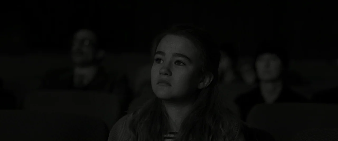 Wonderstruck (2017) movie still: medium — A dark movie theater with rows of seats occupied by silhouetted figures. A teenage girl sits in the…
