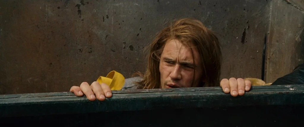 Pineapple Express (2008) movie still: medium — A man peers from inside a large, rusted metal dumpster. He holds onto the upper edge of the bin with…