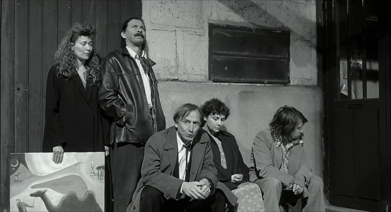 The Bohemian Life (1945) movie still: medium — Five adults are positioned along a rough textured concrete wall outdoors in daylight. They are posed…