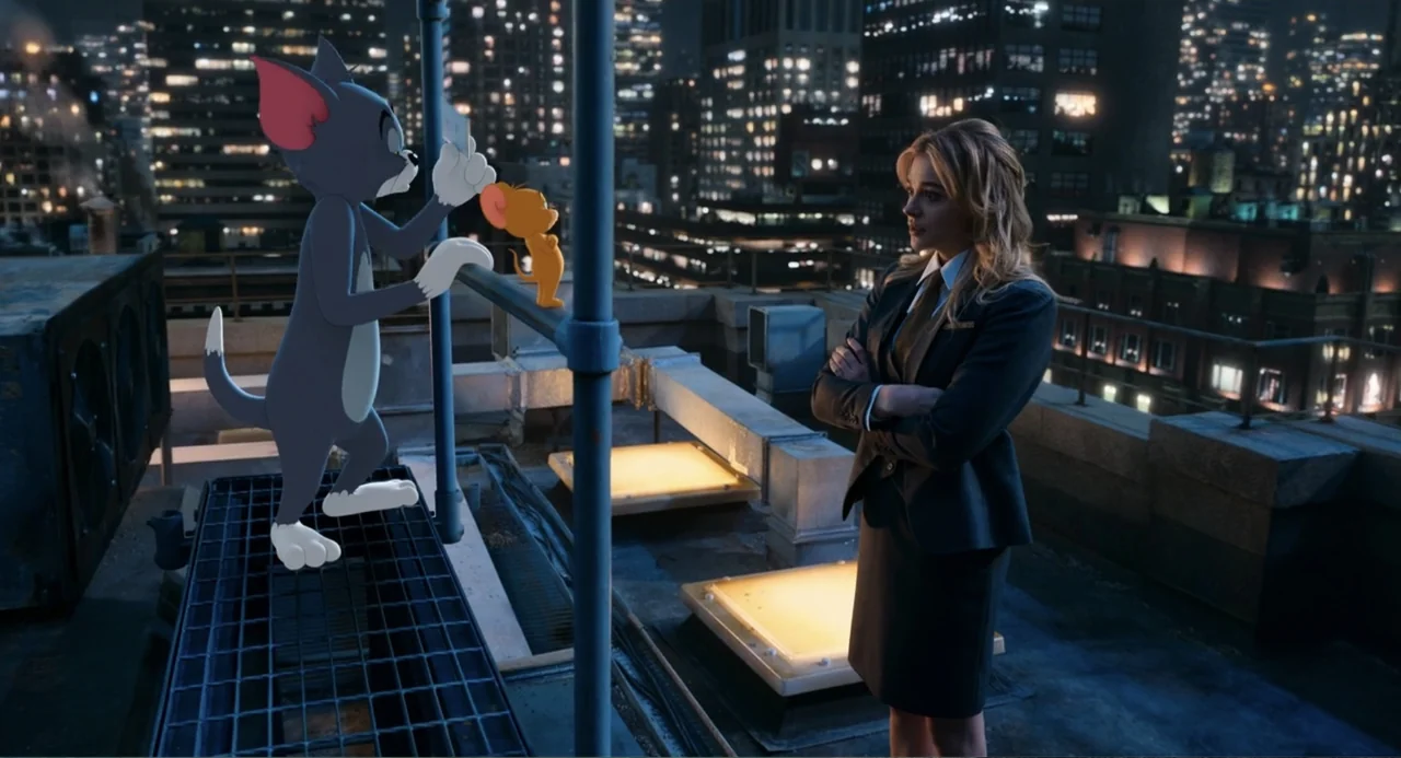 Tom & Jerry (2021) movie still: medium — An urban rooftop at night overlooks a illuminated city skyline with metal industrial structures. A woman in…
