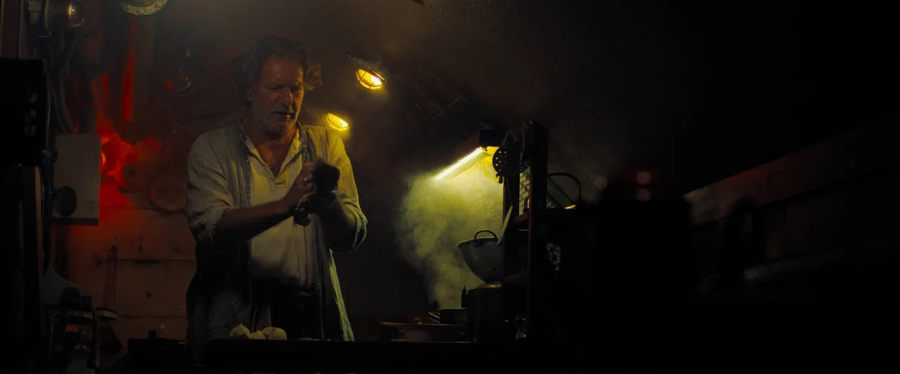 Black Sea (2014) movie still: medium — A cramped and dimly lit galley inside a submarine features dark, utilitarian metal surfaces. A man works…