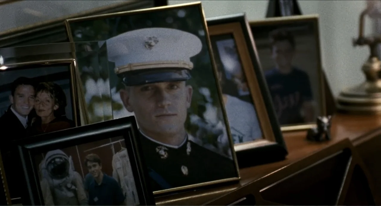 Colin Quinn: Red State, Blue State (2019) movie still: closeup — A wooden shelf holds a collection of various framed photographs in a quiet…