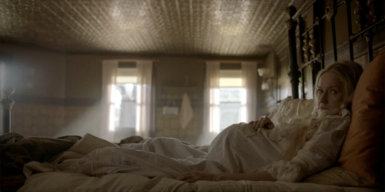 Deadwood: The Movie (2019) movie still: medium — An 1800s style bedroom features a wooden bed frame, patterned ceiling, and sunlit windows. A…