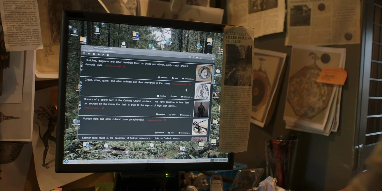 Demonic (2015) movie still: medium — A cluttered computer desk features various notes, newspaper clippings, and occult-related materials pinned to…