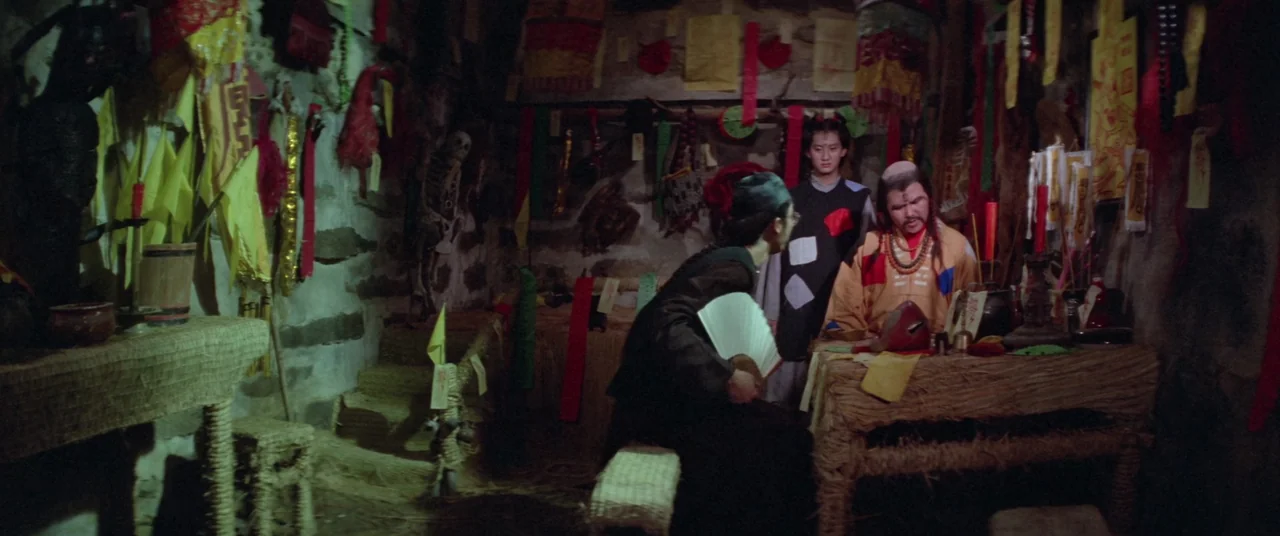 Encounter of the Spooky Kind (1980) movie still: medium — A rustic, stone-walled room is cluttered with ceremonial paper streamers, banners, and…