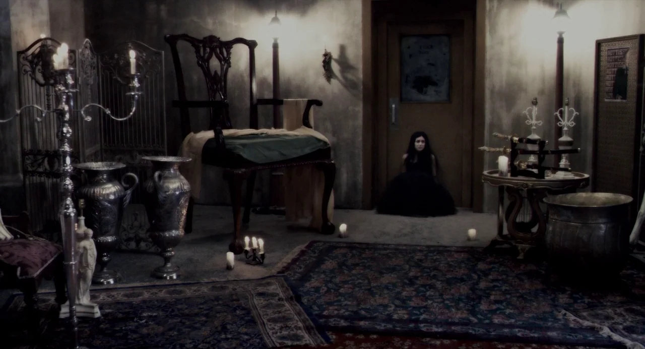 Repo! The Genetic Opera (2008) movie still: wide — A dimly lit room contains ornate antique furniture, metal vases, and scattered floor candles. A…
