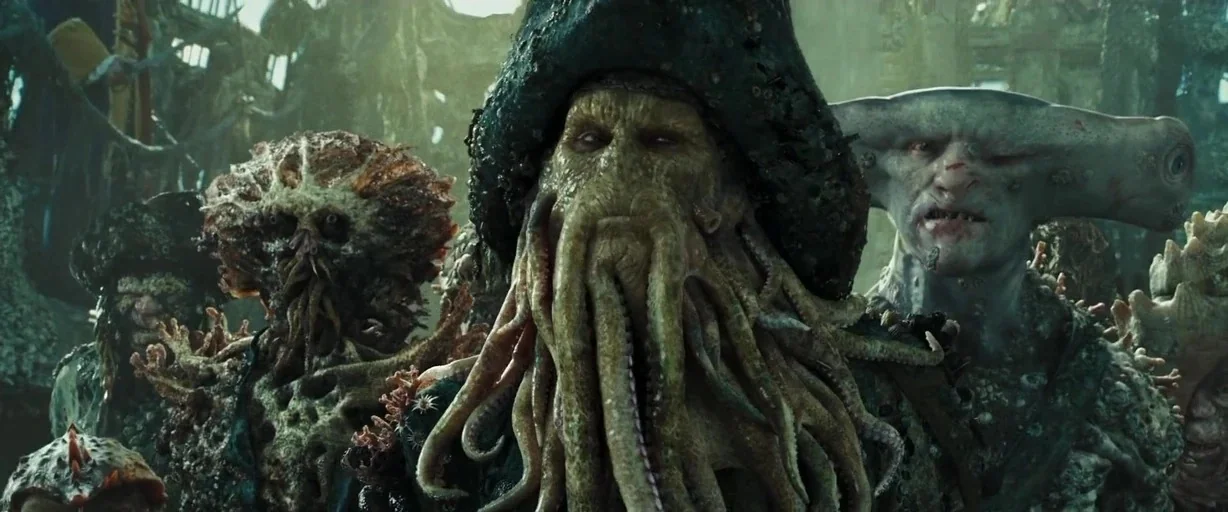 Pirates of the Caribbean: At World’s End movie still: medium — A group of humanoid sea creatures stands aboard a weathered, salt-crusted wooden ship…