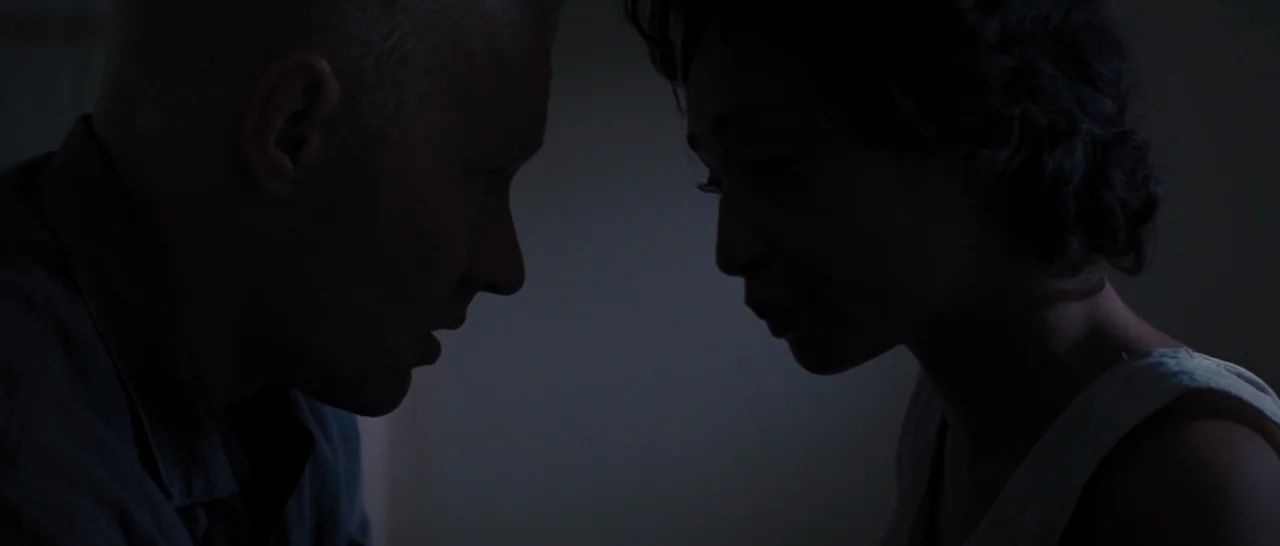 Loving (2016) movie still: medium — A dimly lit room holds two people in shadows. They stand in profile facing one another in the dark.