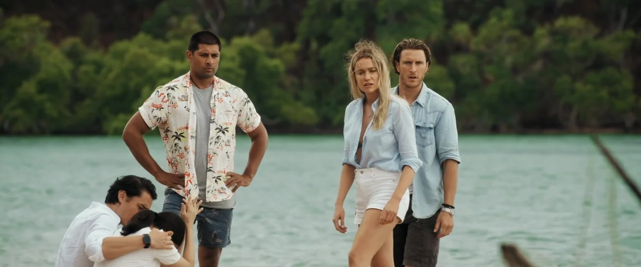 Great White (1998) movie still: fullbody — A group of five people stand on a wooden dock overlooking a tropical bay. They look toward the water with…
