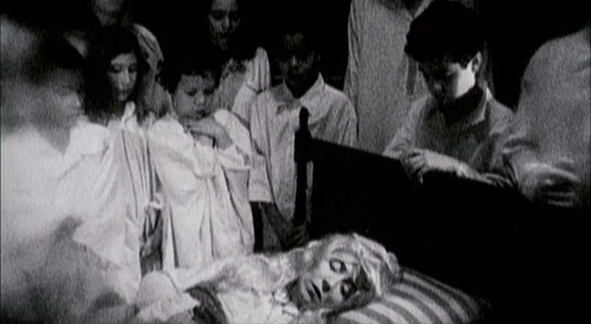 Brand Upon the Brain! (2006) movie still: medium — A dark, crowded bedroom interior features several children gathered around a person on a bed. The…