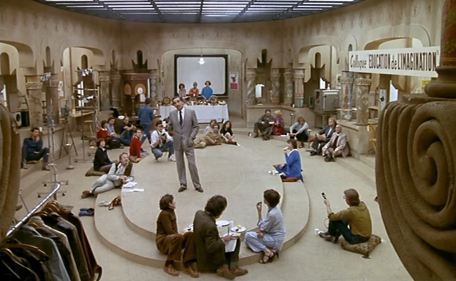 Life Is A Bed of Roses (1983) movie still: wide — A wide circular room features tiered seating platforms and decorative arched pillars. A group of…