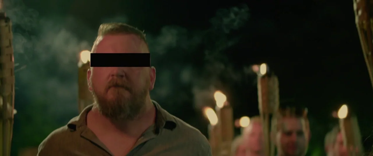 BlacKkKlansman (2018) movie still: medium — A group of people walk through a dark environment at night holding lit torches. The main subject in the…