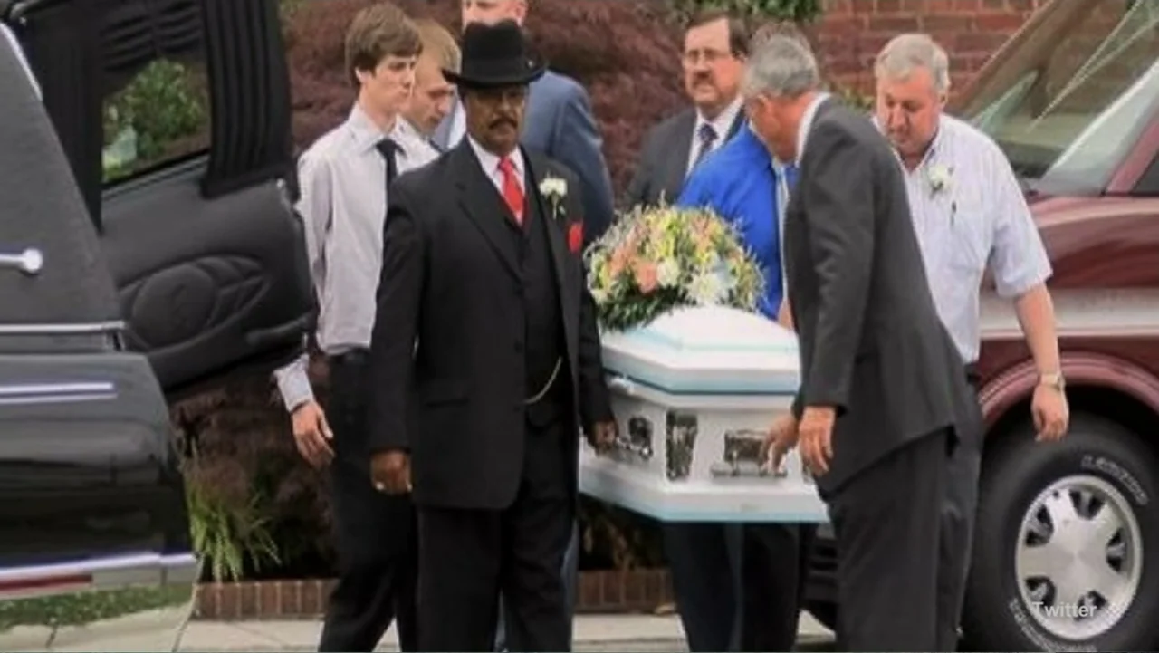 Requiem for the Dead: American Spring 2014 (2015) movie still: medium — A group of men in suits carry a white funeral casket outdoors. The men move…