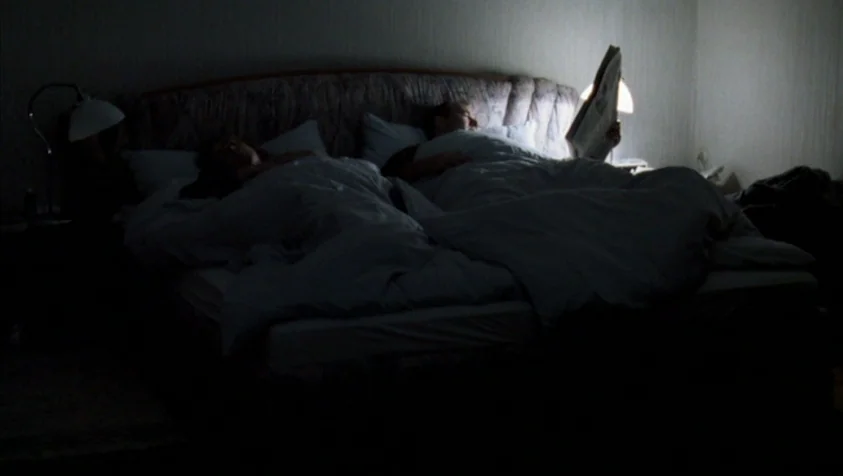 71 Fragments of a Chronology of Chance (1994) movie still: wide — A dark bedroom with two people lying in a large bed at night. A man sits propped…