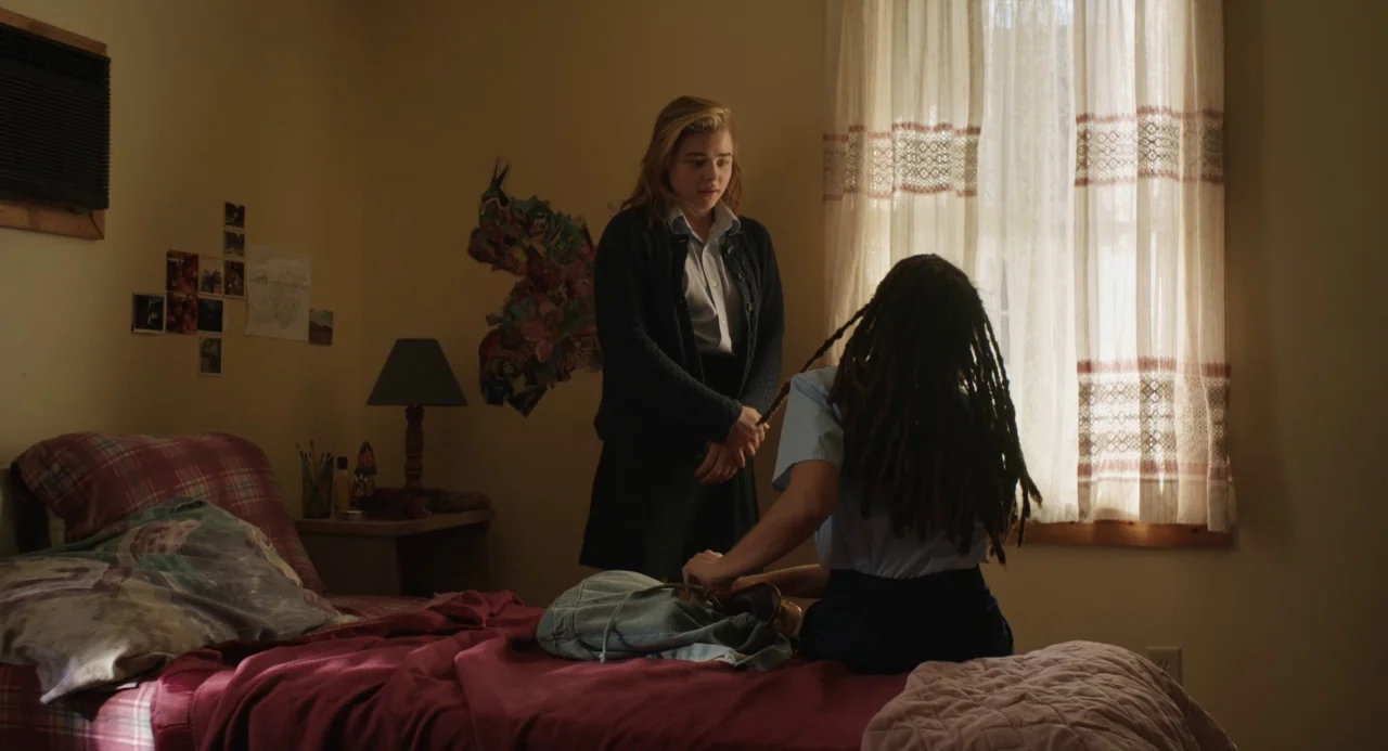 The Miseducation of Cameron Post (2018) movie still: medium — A residential room features a bed covered in a maroon quilt and beige walls. A…