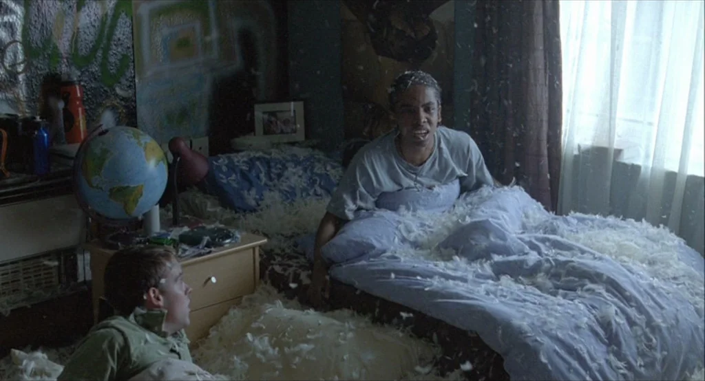 Looking for Eric (2009) movie still: medium — A cluttered room contains a bed covered in loose feathers and a globe lamp. Two people occupy the bed…