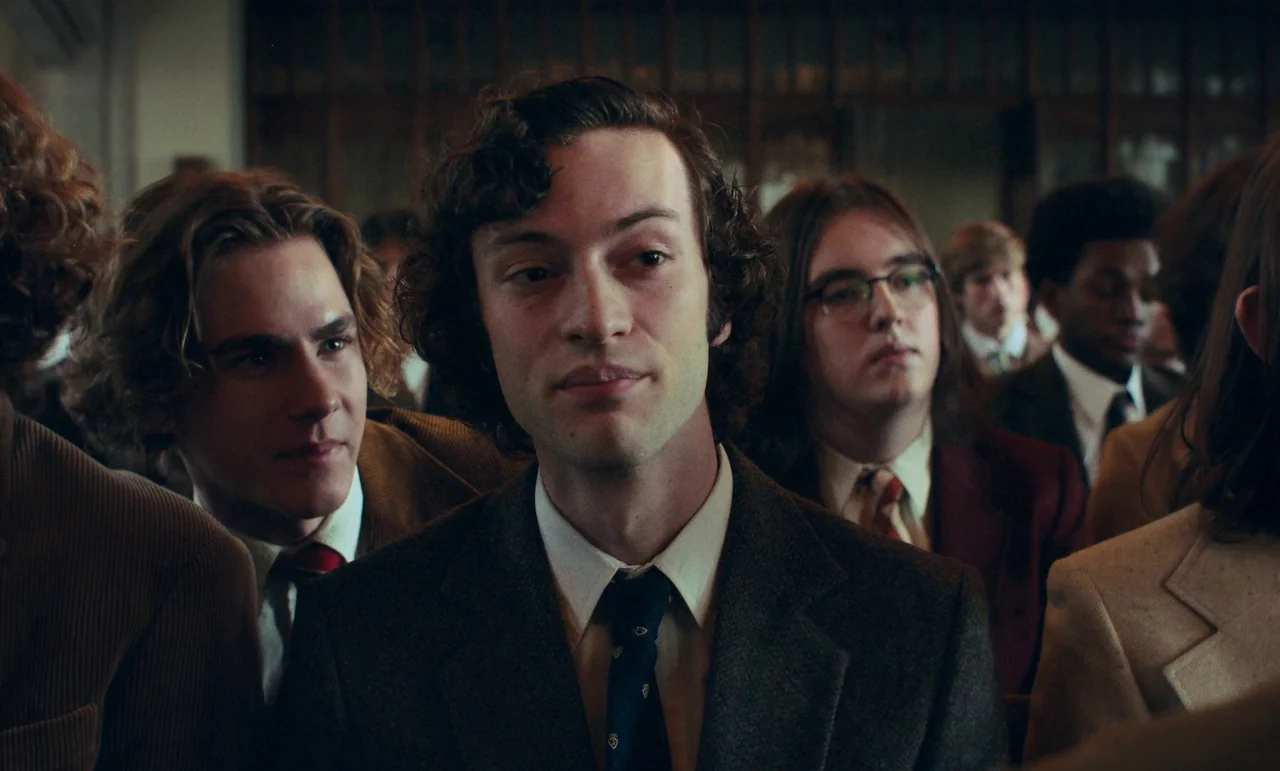 The Holdovers (2023) movie still: medium — A group of young men in formal attire sit closely together in a wood-paneled room. The primary subject…