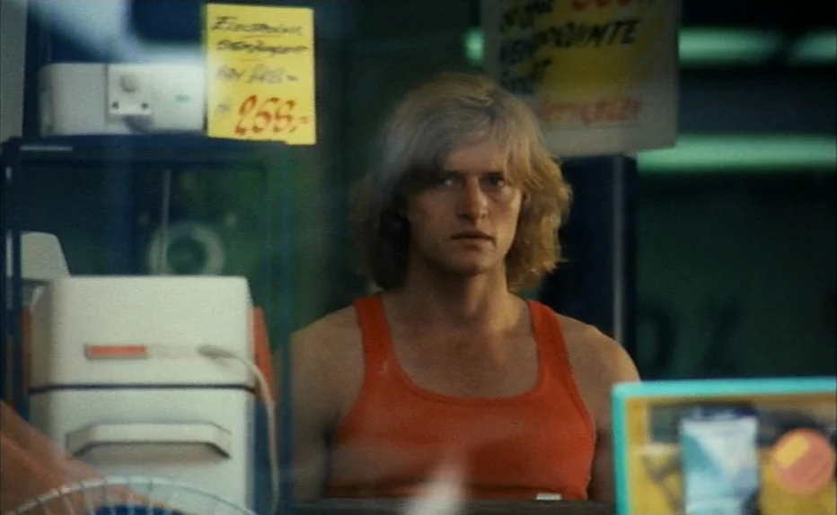 Turkish Delight (1973) movie still: medium — An interior shot through store window glass featuring various retail merchandise in the foreground. A…