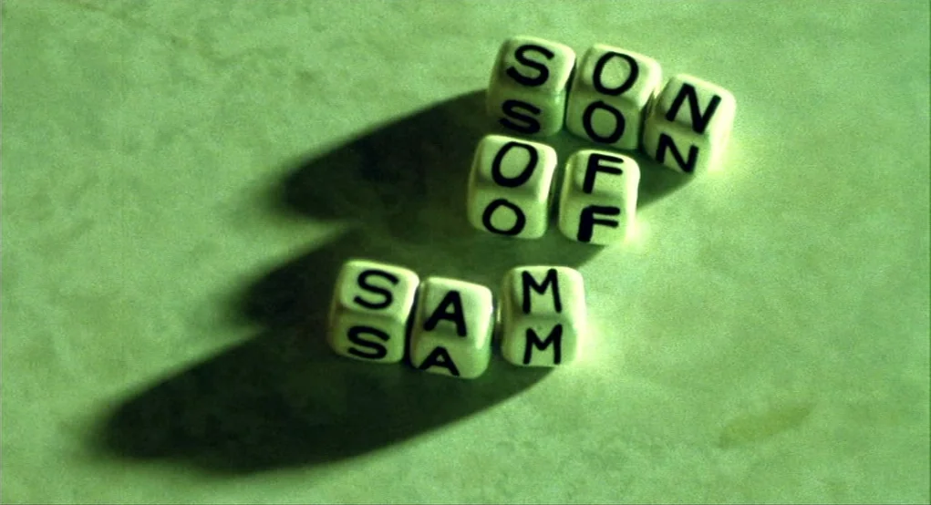 Summer of Sam (1999) movie still: closeup — Small white lettered cubes are arranged on a pale green surface. The cubes spell out the phrase SON OF…
