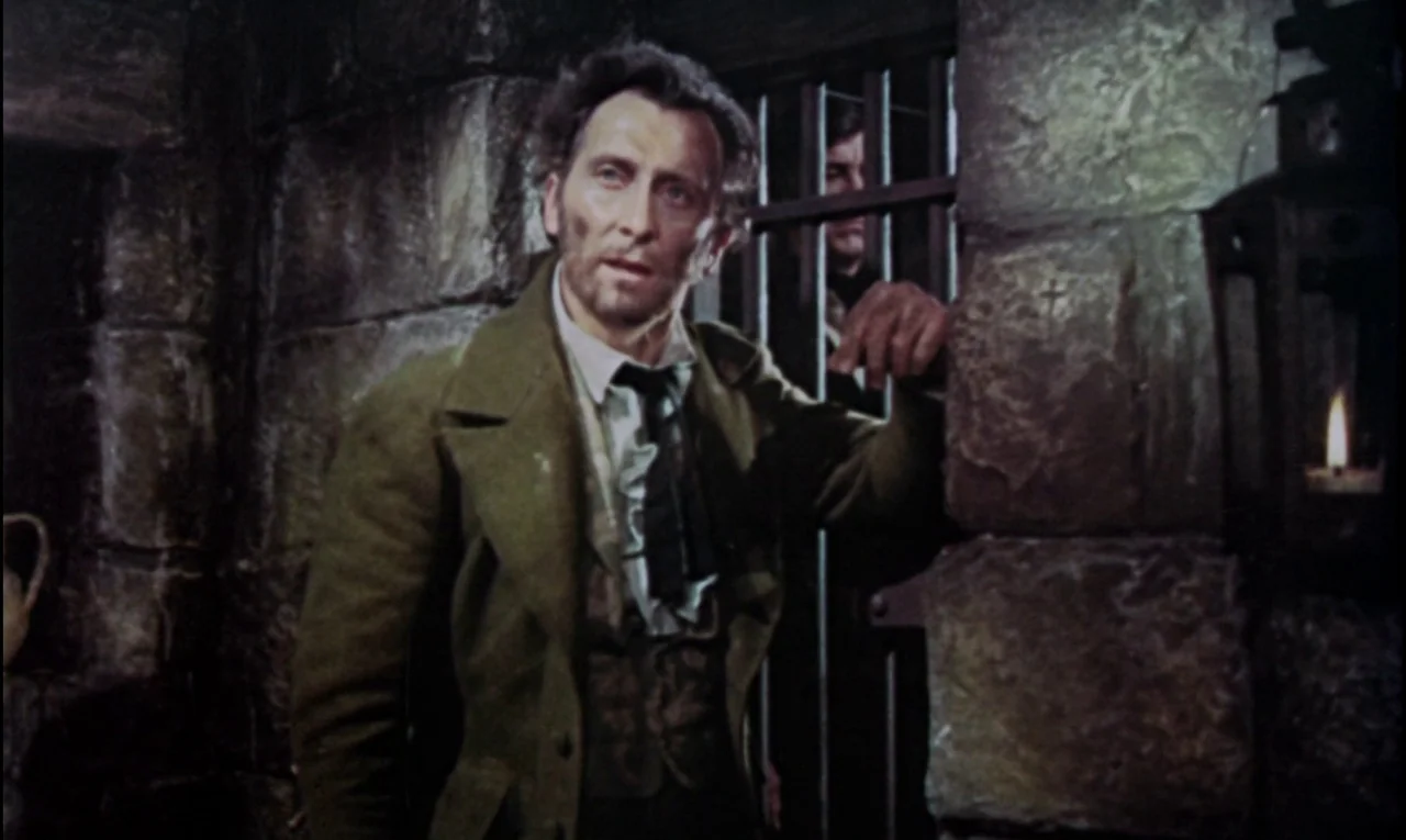 The Curse of Frankenstein (1957) movie still: medium — A stone corridor with heavy blocks and iron bars indicates a subterranean incarceration…