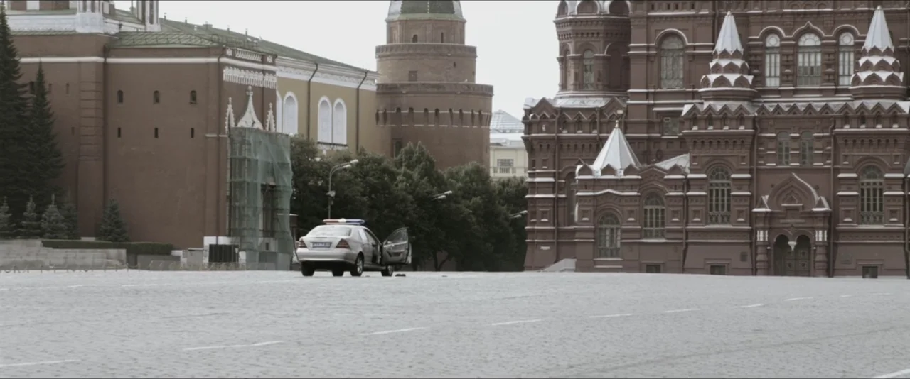 Darkest Hour (2017) movie still: wide — A wide, empty cobblestone plaza is flanked by ornate red brick historic buildings. A solitary silver police…