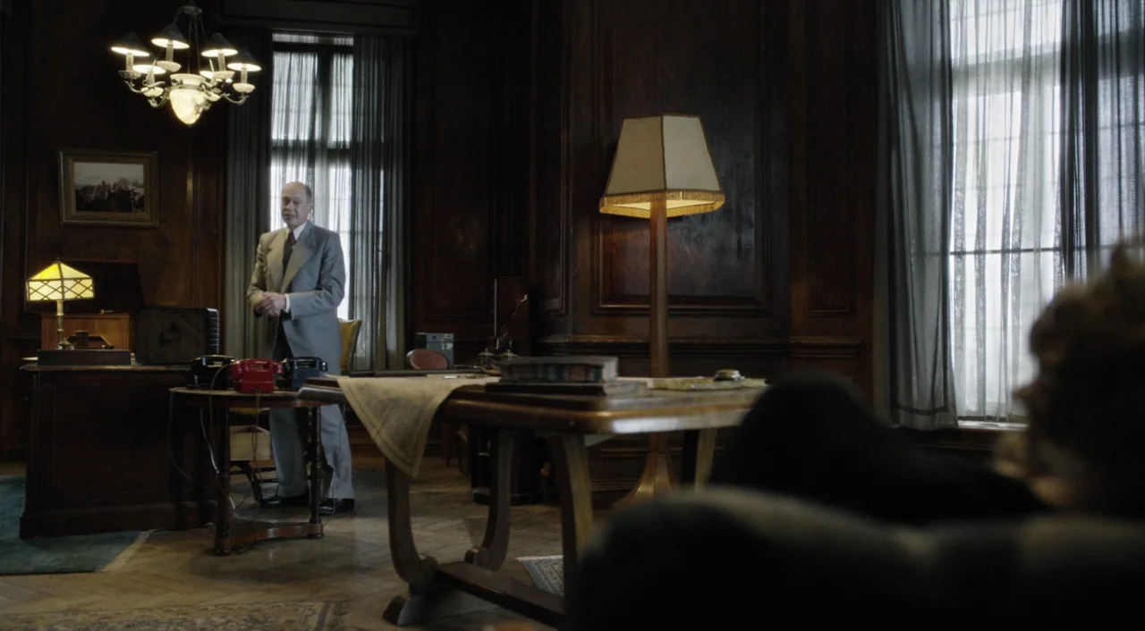 The Death of Stalin (2017) movie still: wide — A dark-paneled room features heavy wood furniture, an ornate chandelier, and sheer window curtains. A…