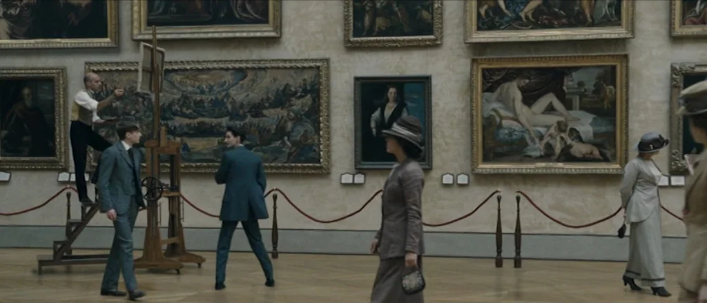 Frantz (2016) movie still: wide — A large museum gallery features numerous framed oil paintings hung on beige-colored walls. Multiple individuals…