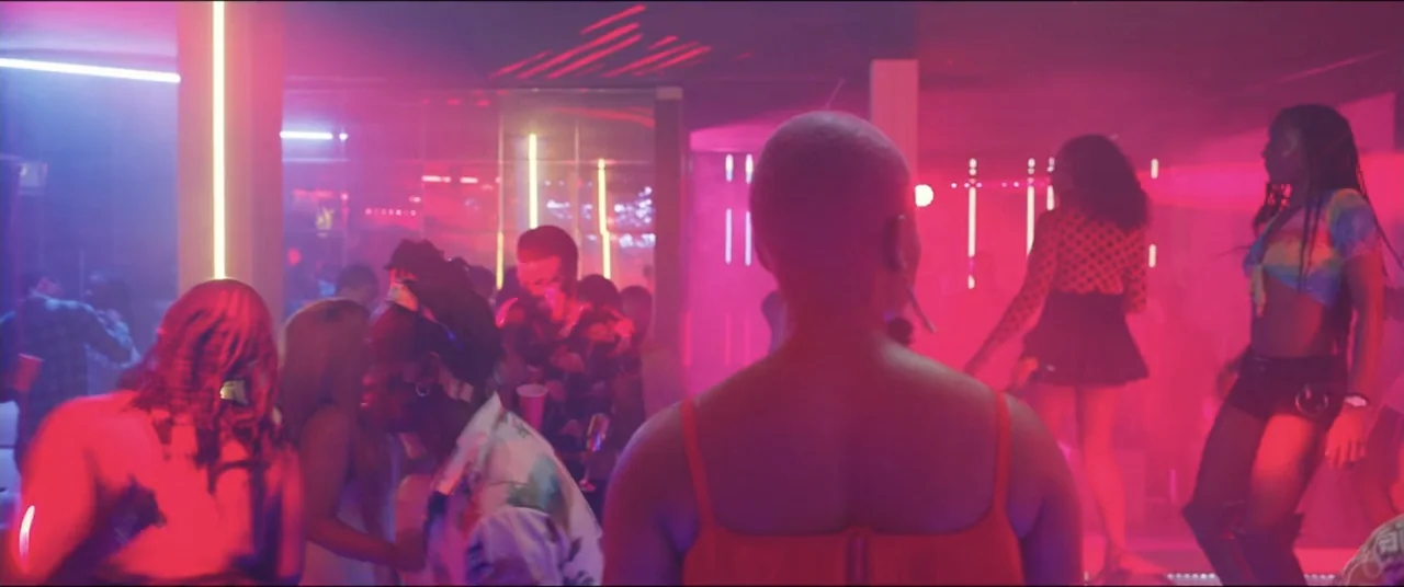 Saving Onome (2024) movie still: medium — A crowded dance floor is filled with people moving under vibrant pink and blue lighting. A person in the…