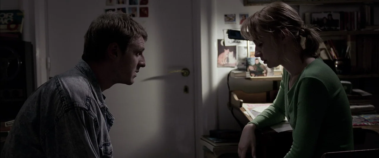 4 months, 3 Weeks and 2 Days (2007) movie still: medium — A cluttered residential room with white doors and various papers taped to the walls. A man…