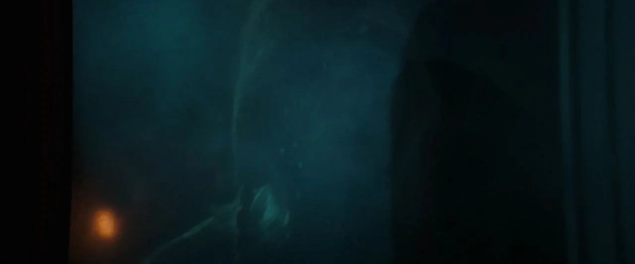Becky (2020) movie still: closeup — A dark train cabin interior at night with reflection on a window pane. A person stands behind the glass looking…