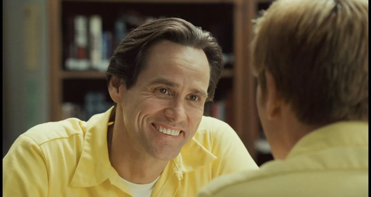 I Love You Phillip Morris (2010) movie still: medium — An interior office space features blurred shelving with books visible in the background. A…