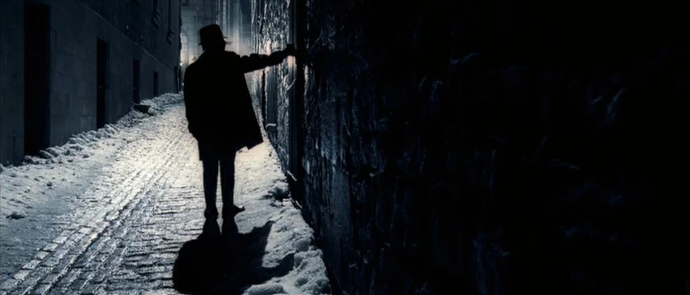 Confessions of a Dangerous Mind (2002) movie still: fullbody — A narrow snow-dusted stone alleyway at night illuminated by a distant street light. A…