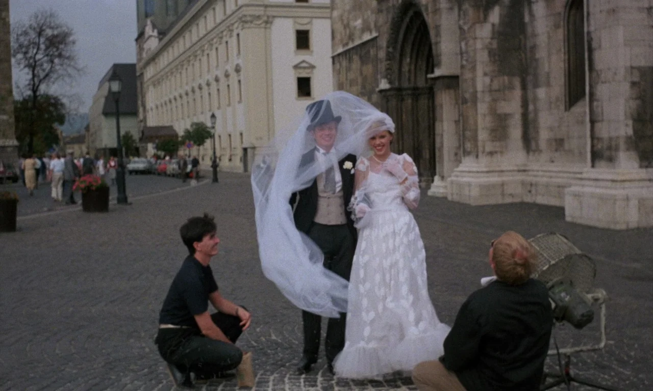 The Church (1989) movie still: fullbody — A stone paved plaza sits in front of a large gothic arched entranceway. A photographer and his assistant…